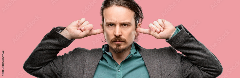 Handsome young man covering ears ignoring annoying loud noise, plugs ears to avoid hearing sound. Noisy music is a problem. Handsome young man covering ears ignoring annoying loud noise, plugs ears to avoid hearing sound. Noisy music is a problem.