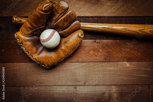 A group of vintage baseball equipment, bats, gloves, baseballs on wooden background