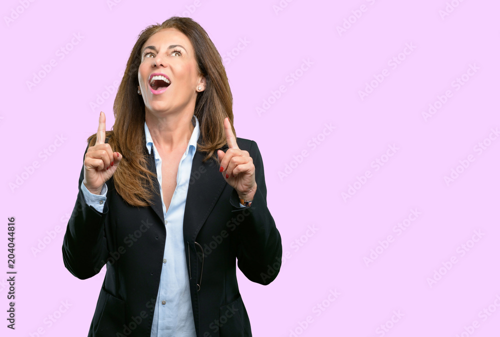 Middle age business woman happy and surprised cheering expressing wow gesture pointing up Middle age business woman happy and surprised cheering expressing wow gesture pointing up