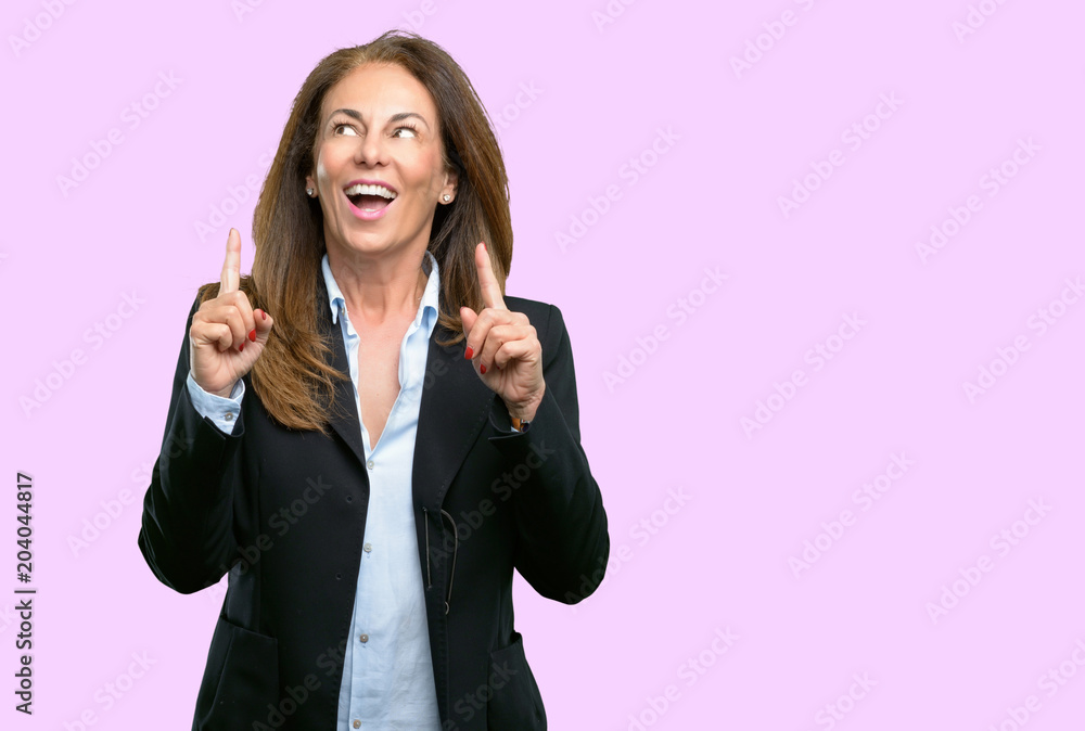 Middle age business woman happy and surprised cheering expressing wow gesture pointing up Middle age business woman happy and surprised cheering expressing wow gesture pointing up