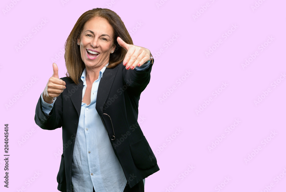 Middle age business woman stand happy and positive with thumbs up approving with a big smile expressing okay gesture Middle age business woman stand happy and positive with thumbs up approving with a big smile expressing okay gesture