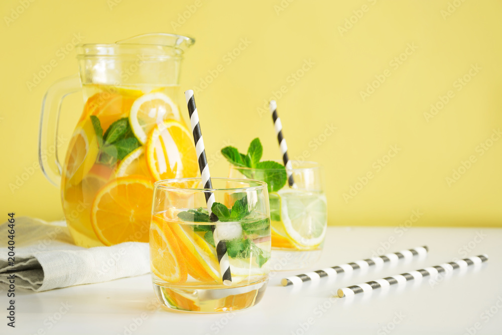 Fototapeta premium Fresh summer lemonade with citrus, orange and mint in glass on yellow background.