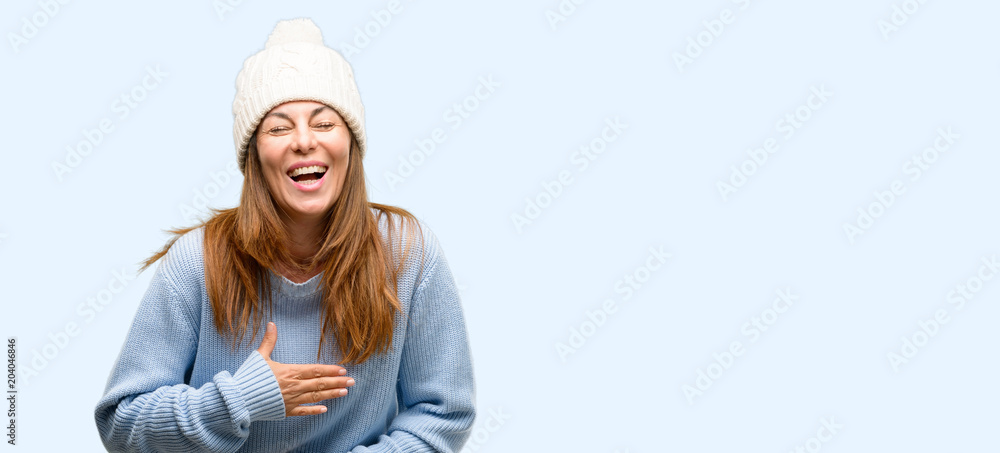 Middle age woman wearing wool winter cap confident and happy with a big natural smile laughing isolated blue background Middle age woman wearing wool winter cap confident and happy with a big natural smile laughing isolated blue background