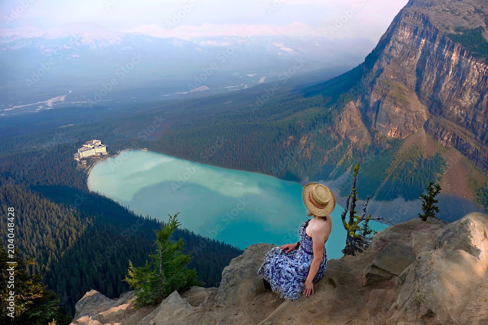 Obraz premium Woman sitting above Lake Louise with beautiful view of Fairmont Chateau hotel. Banff National Park. Canadian Rockies. Alberta. Canada.