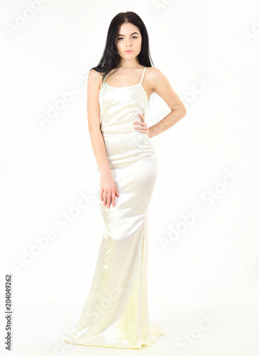 Femininity concept. Fashion model wears expensive fashionable evening dress or wedding dress. Girl on pensive face in graceful dress. Woman in elegant white dress with long hair, white background. © be free