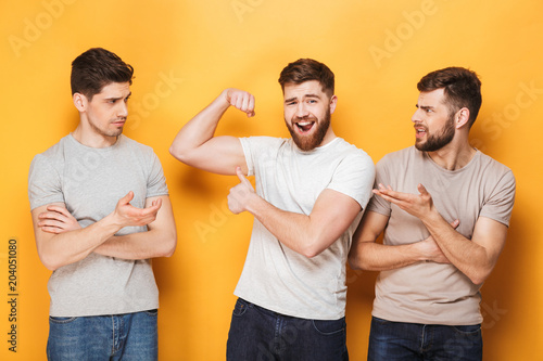 Two young envious men looking at their male friend photo
