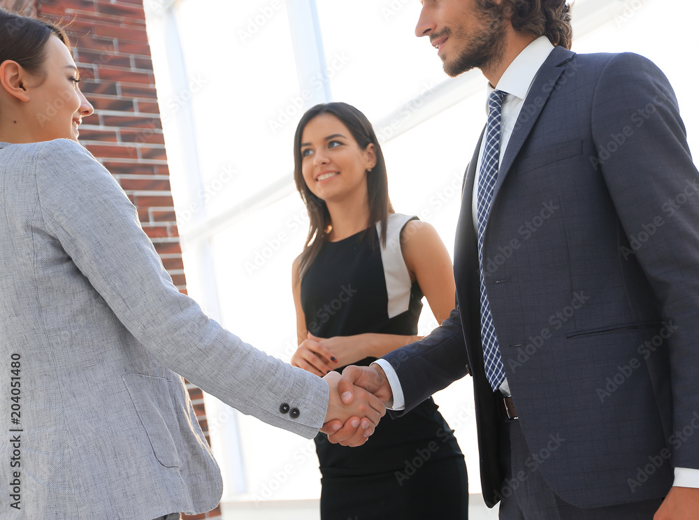 Businesspeople shaking hands against room with large window loo Businesspeople shaking hands against room with large window loo