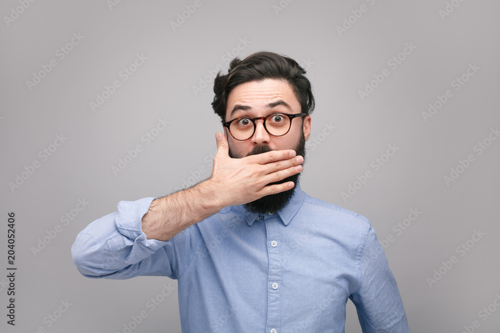 Confused man covering mouth in silence Confused man covering mouth in silence