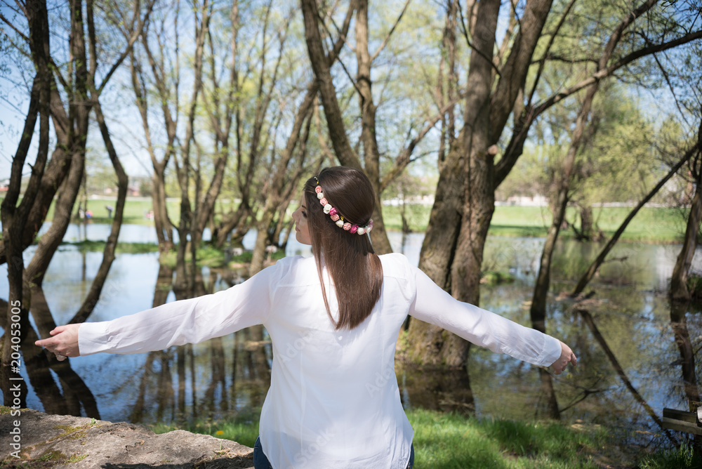 Naklejka premium Young woman sitting on riverbank and enjoying in nature