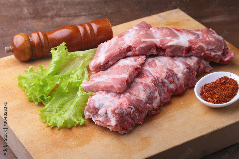 Raw Ribs on a rustic cutting board with salt, pepper and grinder for spices . copy space. Top View. Raw Ribs on a rustic cutting board with salt, pepper and grinder for spices . copy space. Top View.