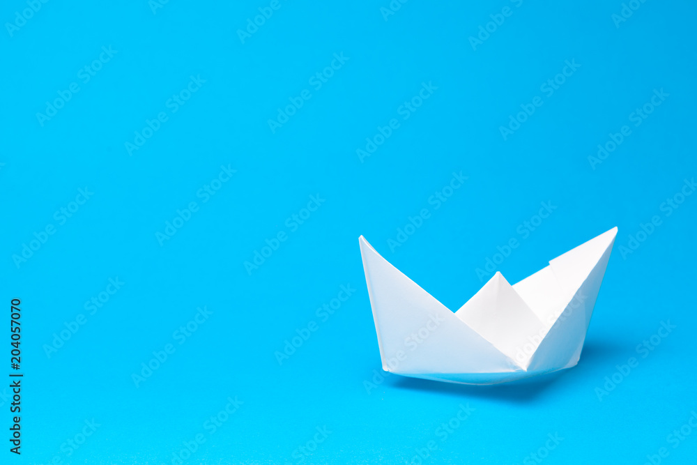 Origami paper boat on blue background Origami paper boat on blue background