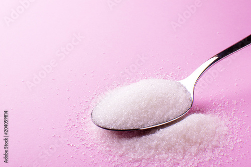 spoon with sugar on a pink background, side view photo