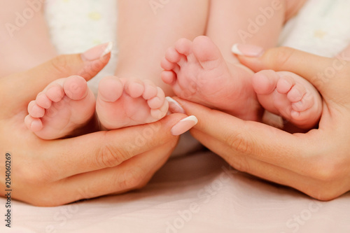 Mother holding tiny feet of her twin babies. New life and family values. Love and tenderness © Zoja