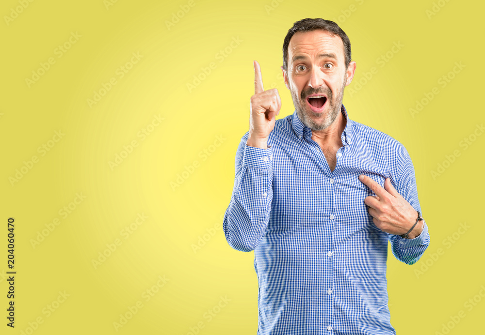 Handsome middle age man happy and surprised cheering expressing wow gesture pointing up