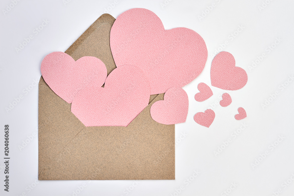 Opened envelope and pink paper hearts. Valentines Day envelope from craft paper and decorative hearts on white backgound. Express your love with letter.