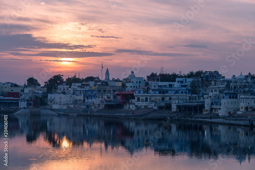 Colorful sky and clouds over Pushkar, Rajasthan, India. Temples, buildings and colors reflecting on the holy water of the lake at sunset.
