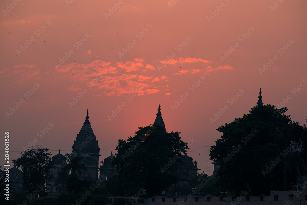 Buildings silhouette at sunset in India. Red orange purple colorful sky. Travel concept. Orchha temple complex.