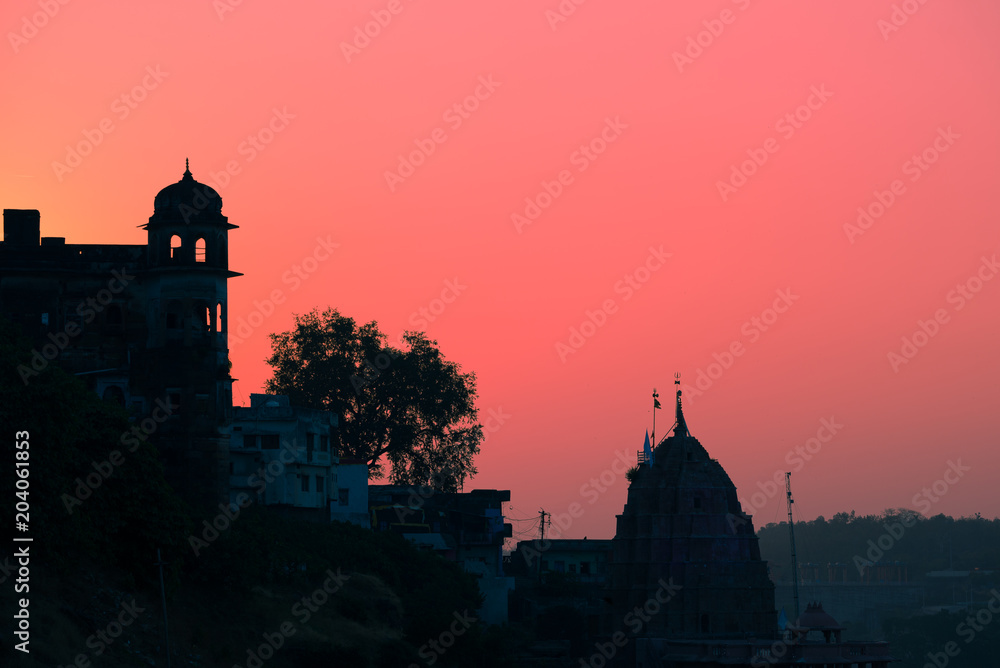 Buildings silhouette at sunset in India. Red orange purple colorful sky. Travel concept. Maheshwar palace and temple complex.