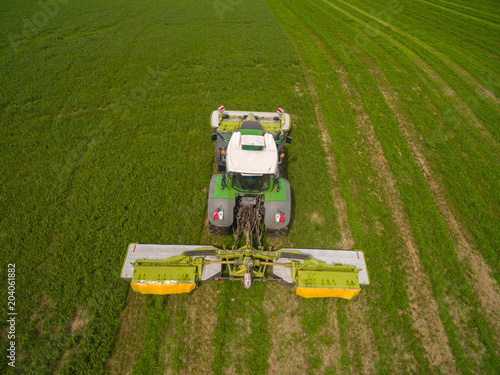 Wallpaper Mural Aerial view of a tractor mowing a green fresh grass field, 
a farmer in a modern tractor mowing a green fresh grass field on a sunny day Torontodigital.ca