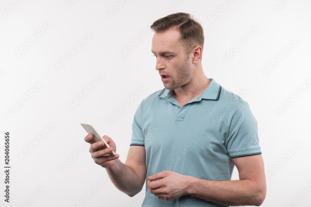 Mobile phone. Pleasant nice man holding his gadget while looking at its screen Mobile phone. Pleasant nice man holding his gadget while looking at its screen