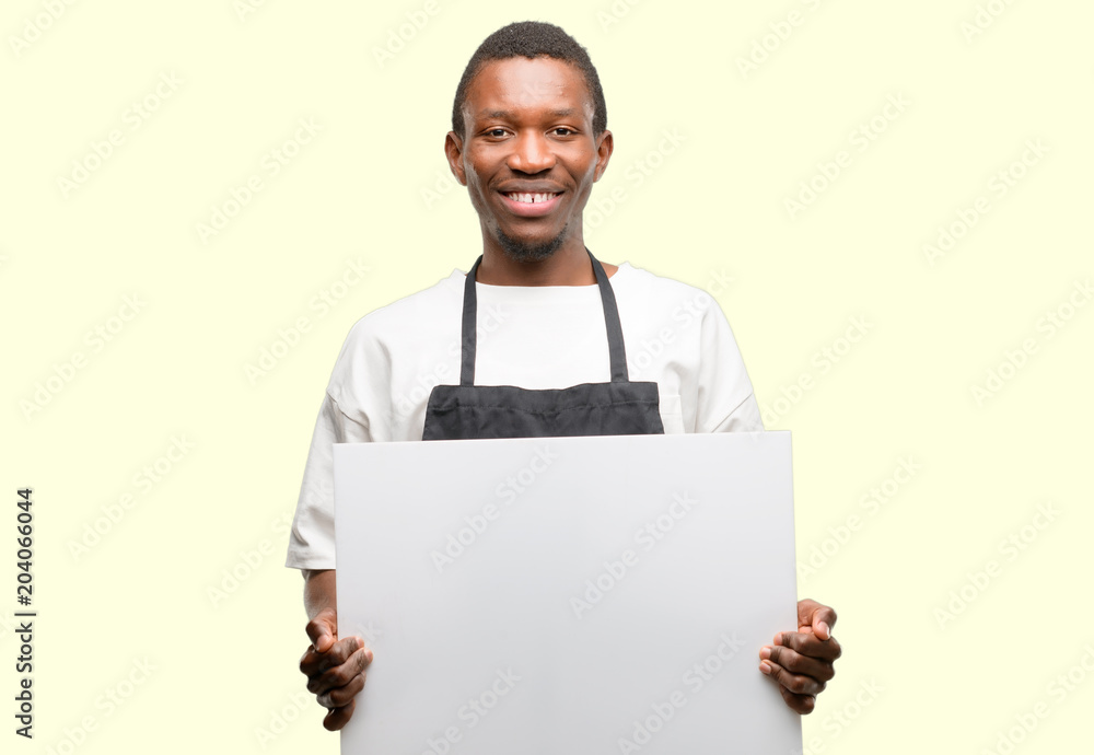 African man shop owner wearing apron holding blank advertising banner, good poster for ad, offer or announcement, big paper billboard African man shop owner wearing apron holding blank advertising banner, good poster for ad, offer or announcement, big paper billboard