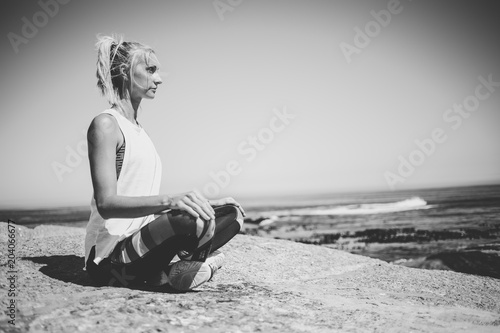 Blond female fitness model meditating and doing yoga on a granite rock overlooking the ocean © Dewald