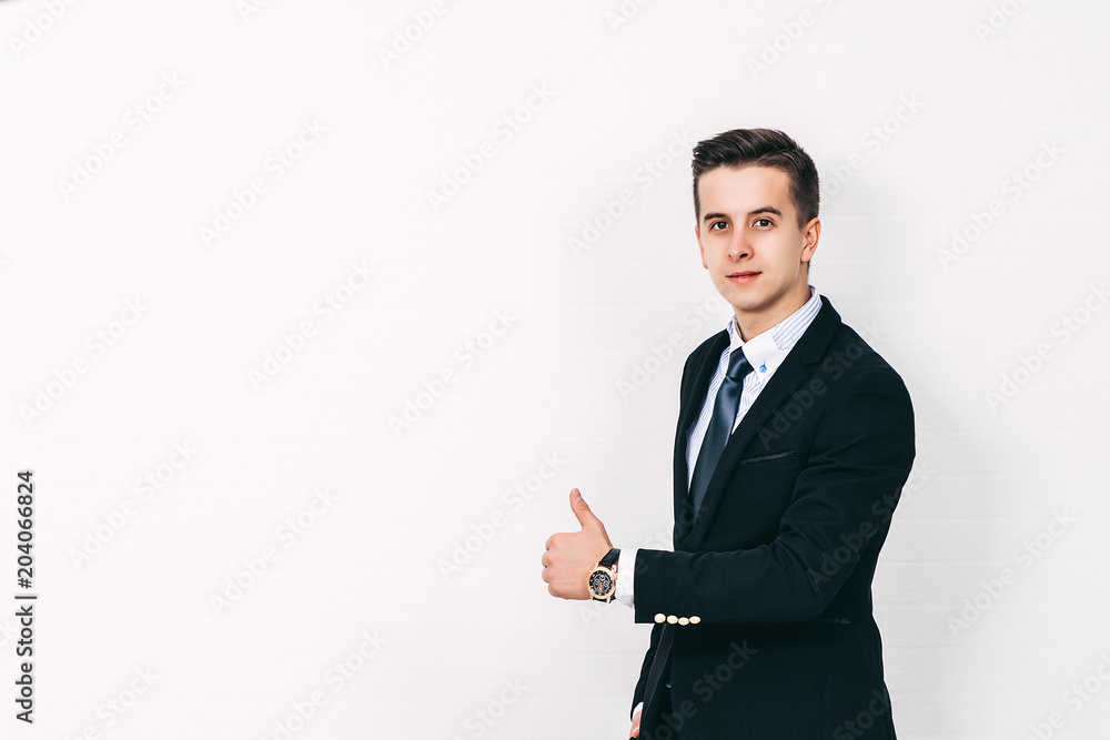 Young Businessman giving a thumbs up sign standing near white backgroung. Businesss concept. Young Businessman giving a thumbs up sign standing near white backgroung. Businesss concept.