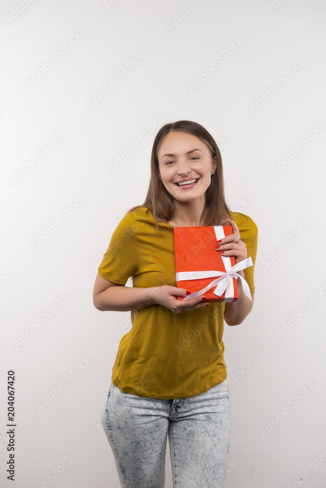 Pleasant gift. Joyful attractive woman holding a gift box while showing her present to you Pleasant gift. Joyful attractive woman holding a gift box while showing her present to you