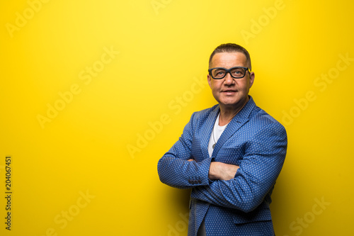 Portrait of happy fun middle age man in suit and eyesglasses isolated on yellow background © F8  \ Suport Ukraine