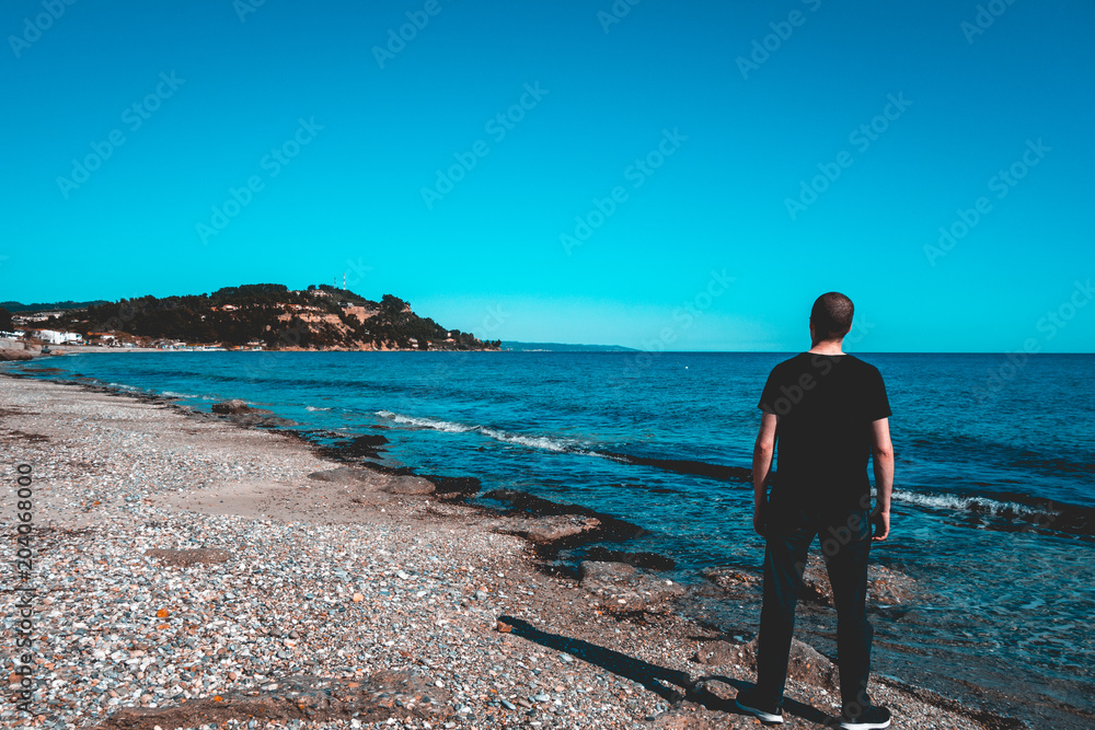 man on a lone beach is watching at the nature