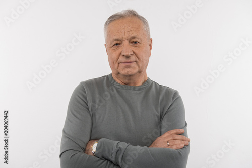 Thoughtful look. Nice aged man standing cross handed while looking at you