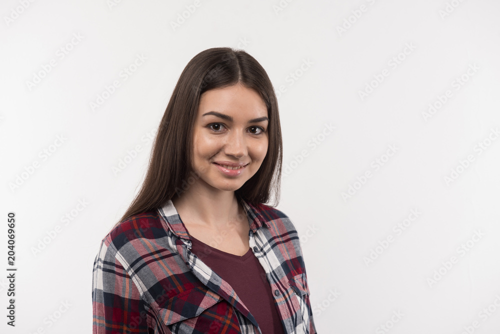 Positive smile. Pleasant delighted woman smiling to you while standing against white background Positive smile. Pleasant delighted woman smiling to you while standing against white background