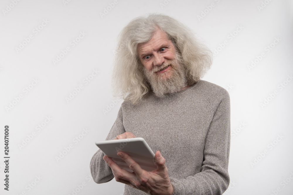 Innovative tablet. Happy nice man smiling while using a digital device Innovative tablet. Happy nice man smiling while using a digital device