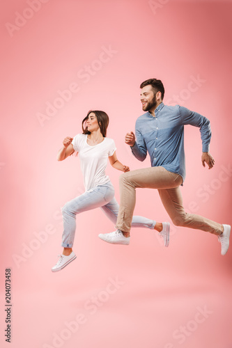 Full length portrait of a funny young couple running fast