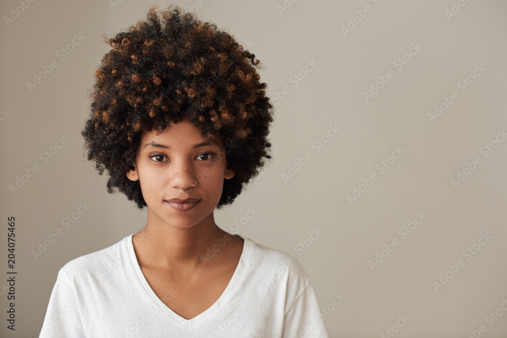 Natural looking young African woman standing against a gray background Natural looking young African woman standing against a gray background