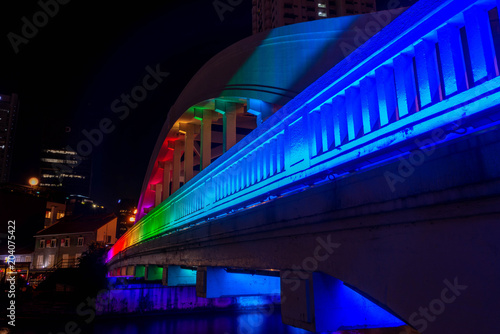 Rainbow colors light the Elgin Bridge at night in downtown Singapore