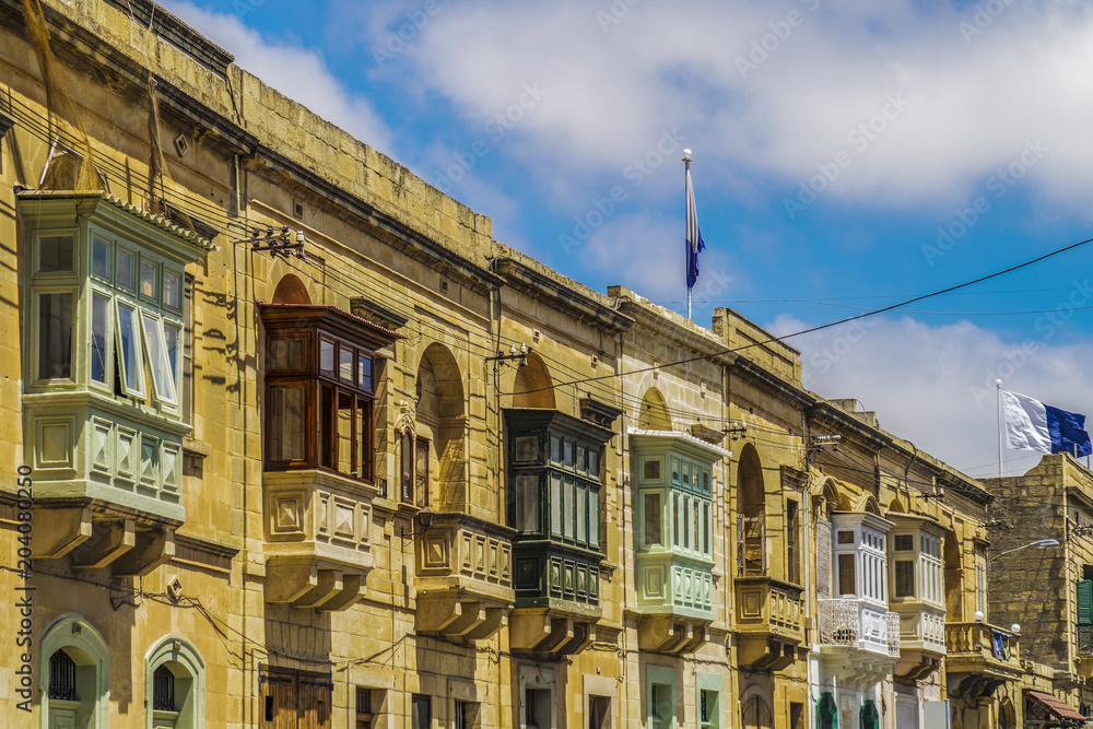 Fototapeta premium Gozo, Malta traditional buildings with colored balconies. Day view of Maltese limestone buildings at Triq Sant Orsola street Victoria Town, Malta.