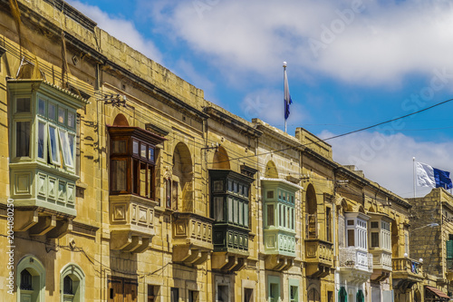 Gozo, Malta traditional buildings with colored balconies. Day view of Maltese limestone buildings at Triq Sant Orsola street Victoria Town, Malta. photo