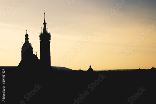 Black silhouette St. Mary Basilica in Krakow and panorama of the city center against a background of sunset and a fantastic beige amber sky