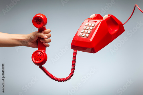 Hand holding telephone, classic red telephone receiver