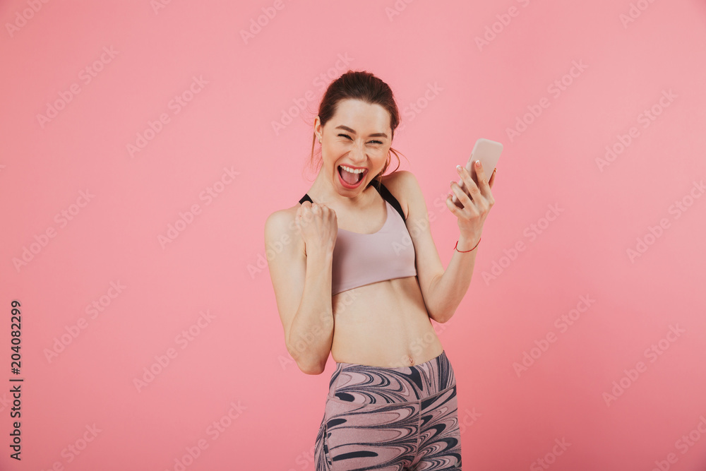Joyful screaming sportswoman holding smartphone and rejoices Joyful screaming sportswoman holding smartphone and rejoices