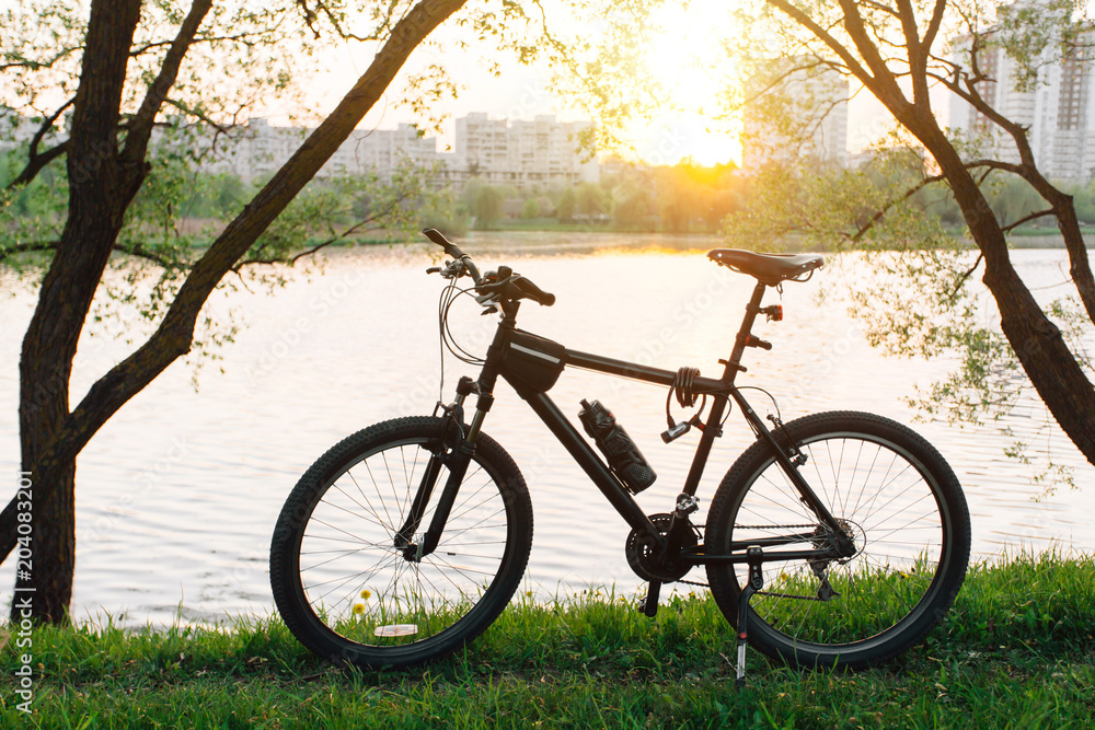 mountain bicycle standing near lake on sunset.