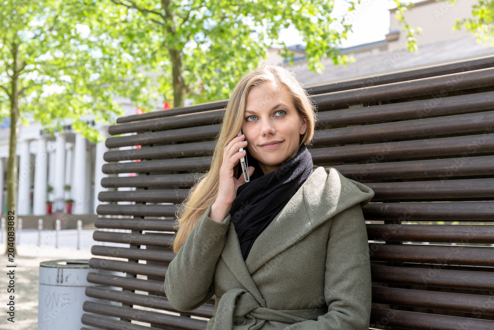 Fototapeta premium Young woman on park bench using smartphone