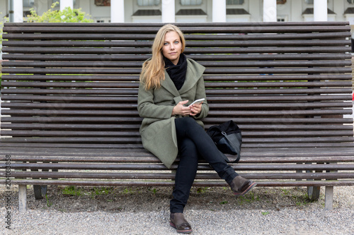 Young beautiful friendly woman sitting on a park bench © orinocoArt