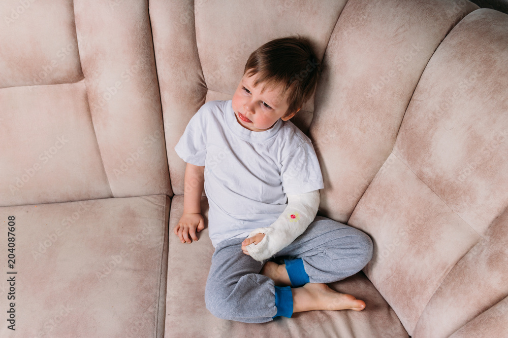 a small boy is sitting on a chair with a broken arm, in a cast. hospital. medicine. danger. pain. to break limbs. violence. a small boy is sitting on a chair with a broken arm, in a cast. hospital. medicine. danger. pain. to break limbs. violence.