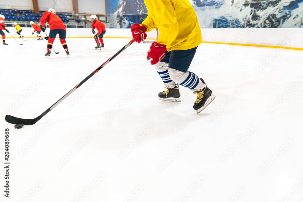 Obraz premium Hockey player in a yellow tank top and red gloves for people drives the puck. Training game, the object is blurred in dynamics.
