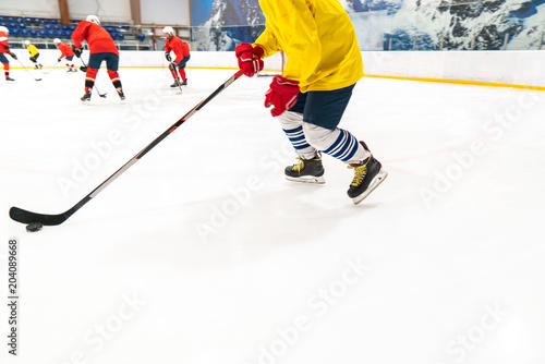 Hockey player in a yellow tank top and red gloves for people drives the puck. Training game, the object is blurred in dynamics.
