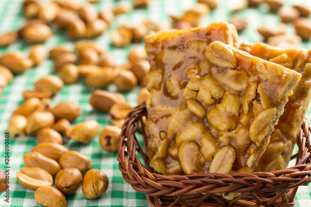 Candy with peanut: Pe de Moleque in Brazil and Chikki in India. Sweet food  of Festa Junina, a typical brazilian party. Snack on wicker basket and  green background. Stock Photo | Adobe