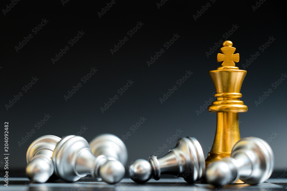 Gold king chess piece win over lying down pawn on black background