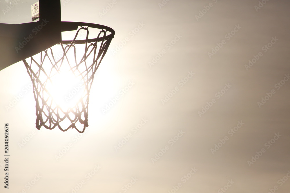 Empty Basketball Hoop, Backboard and Net in Silhouette with Setting Sun Gleaming Through Directly Behind at Quiet Waters Park, Deerfield Beach, Florida